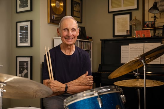 Joe sitting behind his drumset, holding drumsticks