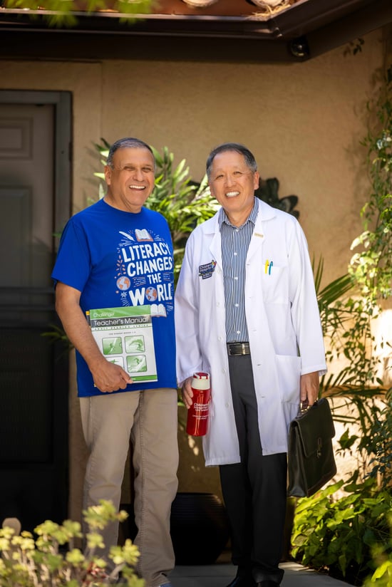 Two men standing in front of a home's front door, smiling for a photo.