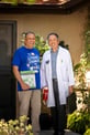 Two men standing in front of a home's front door, smiling for a photo.