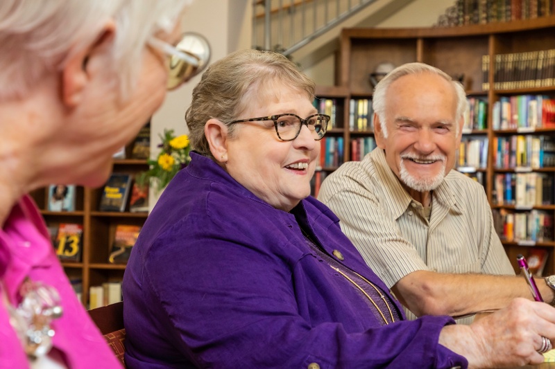 People sitting at a table together in a library. 