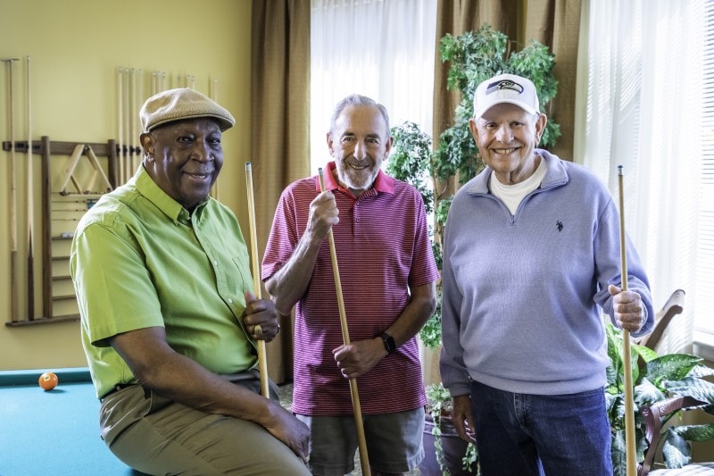 Three men standing by a pool table