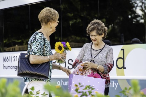 Two women holding flowers and handbags