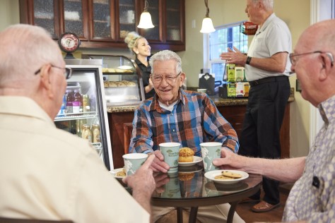 Three men sitting at a table drinking coffee