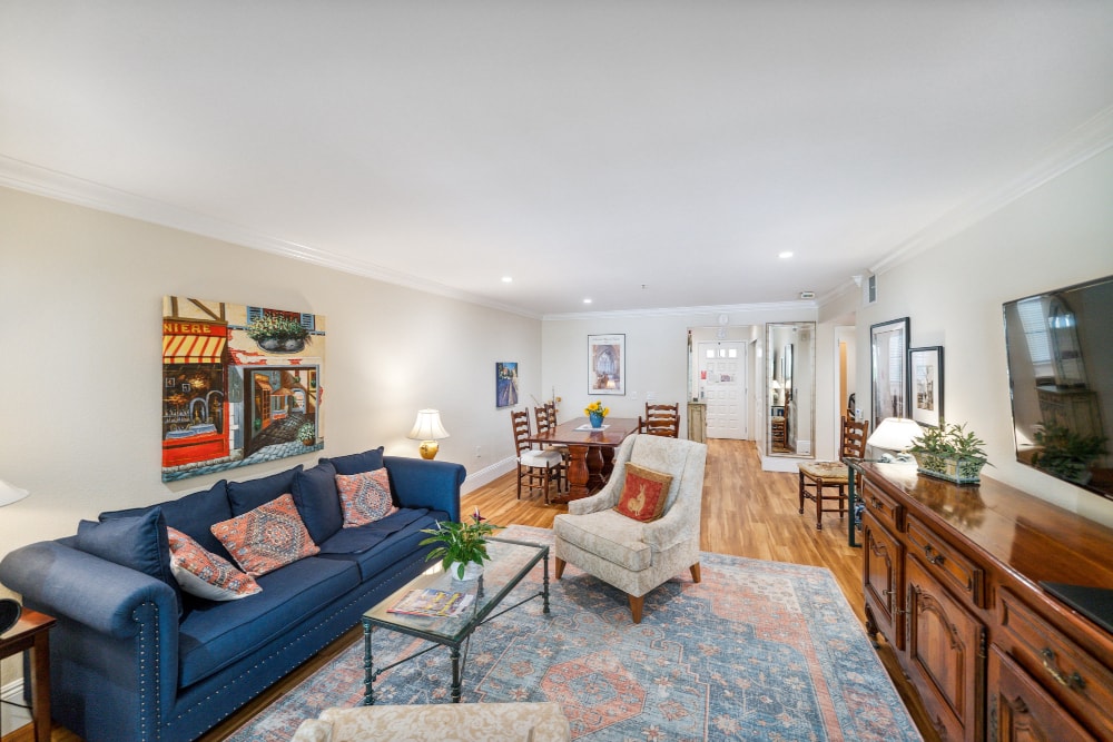 An open living room with sofa, chair, television, and dining room