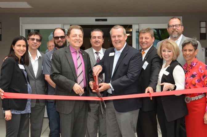 A group cutting a ribbon with big scissors.