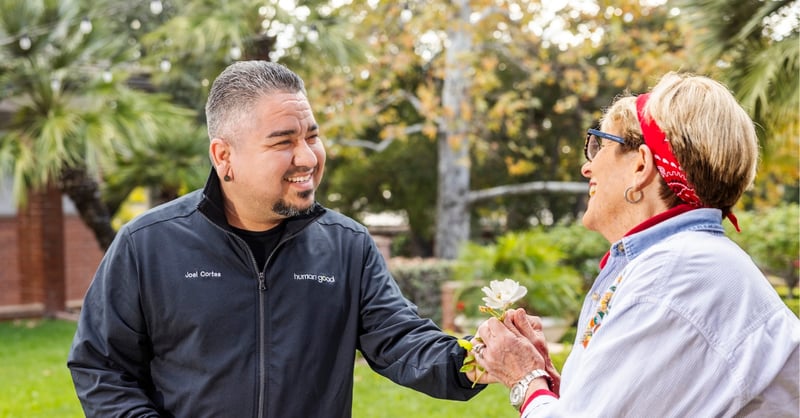 HumanGood team member offering a flower to a resident outdoors at a Life Plan Community