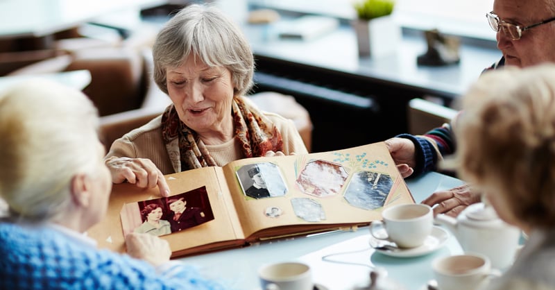 Woman shares a photo album with friends at a café.