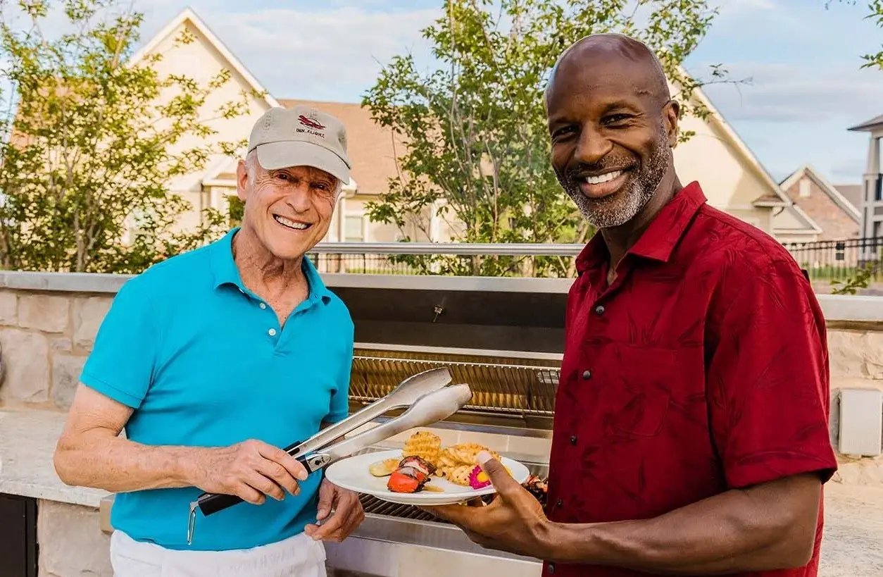 Two men in front of a bbq grill.