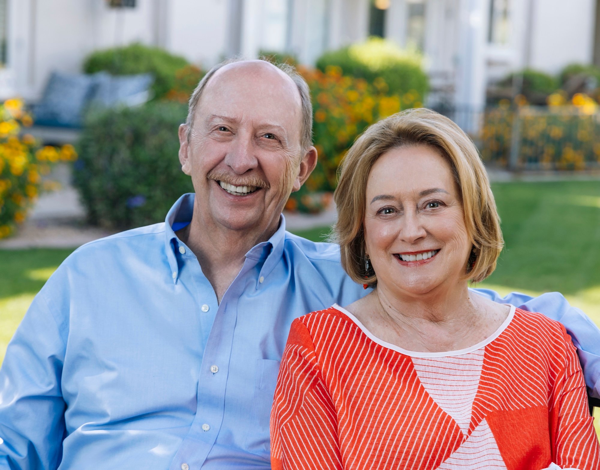 Senior couple sitting outside on bench in gardens