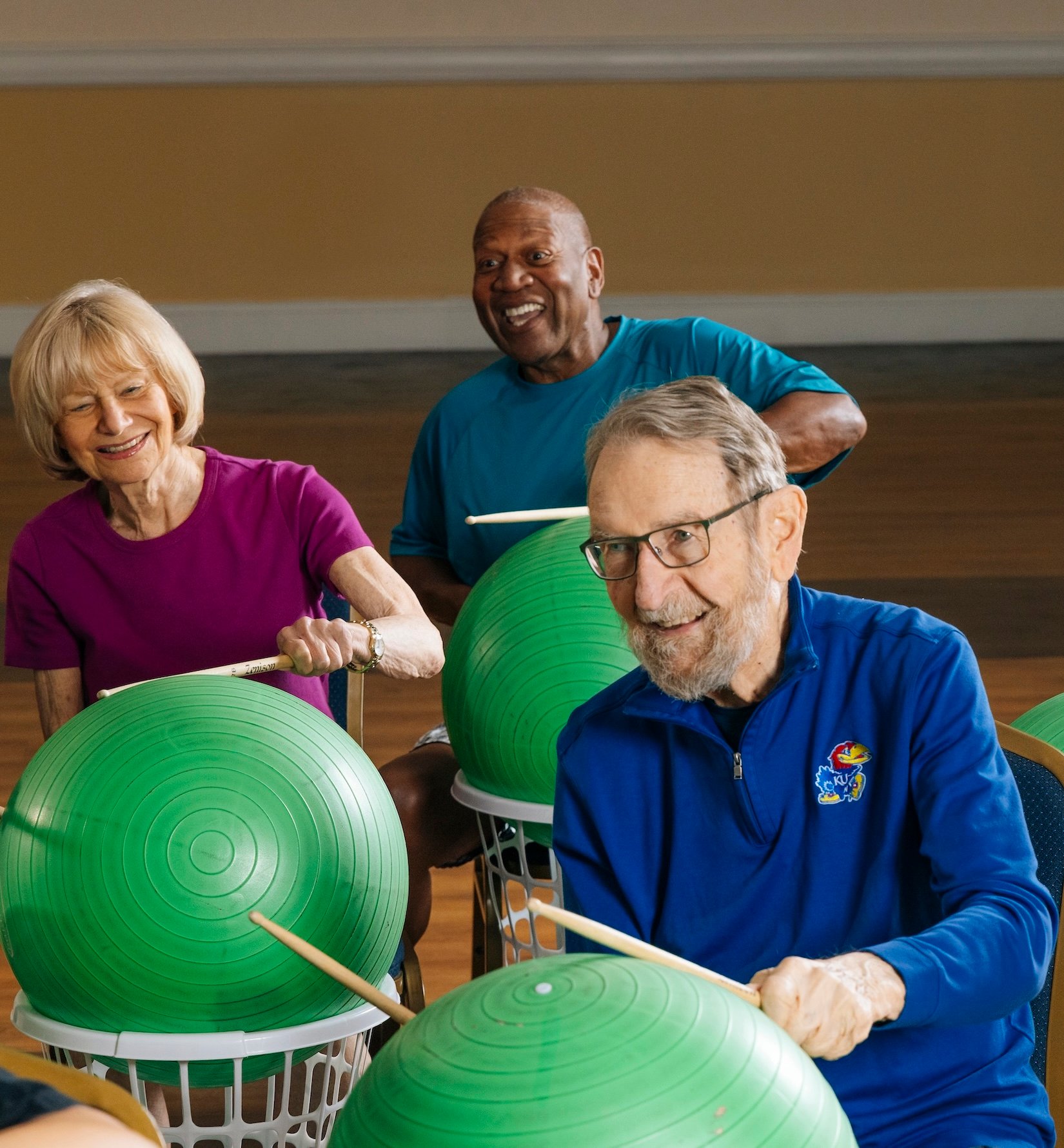 Three residents drumming on yoga balls in group class