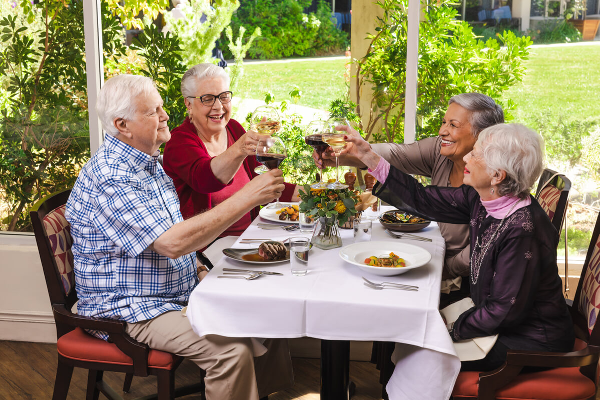 Four senior residents clink their glasses over dinner.