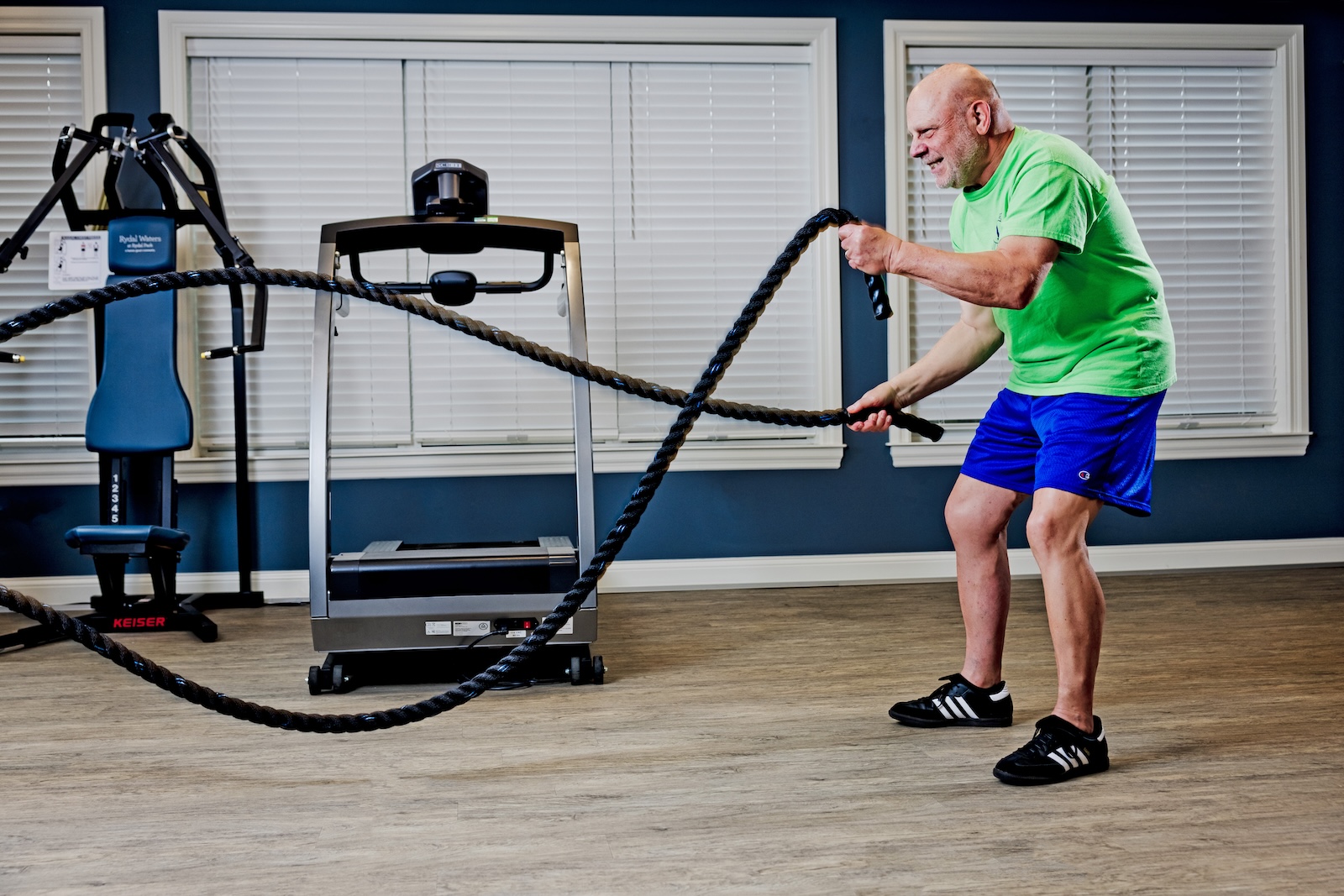Senior man working out with battle ropes in a fitness center