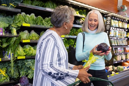 Two senior women shopping for produce in a grocery store