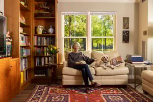 A senior resident and her dog sitting on her couch.