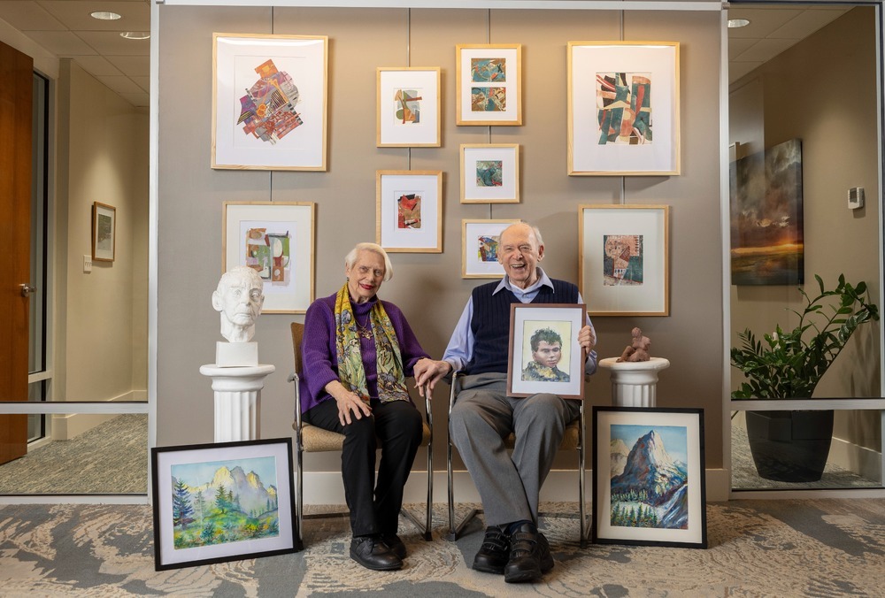Couple sits in a gallery beside framed artwork