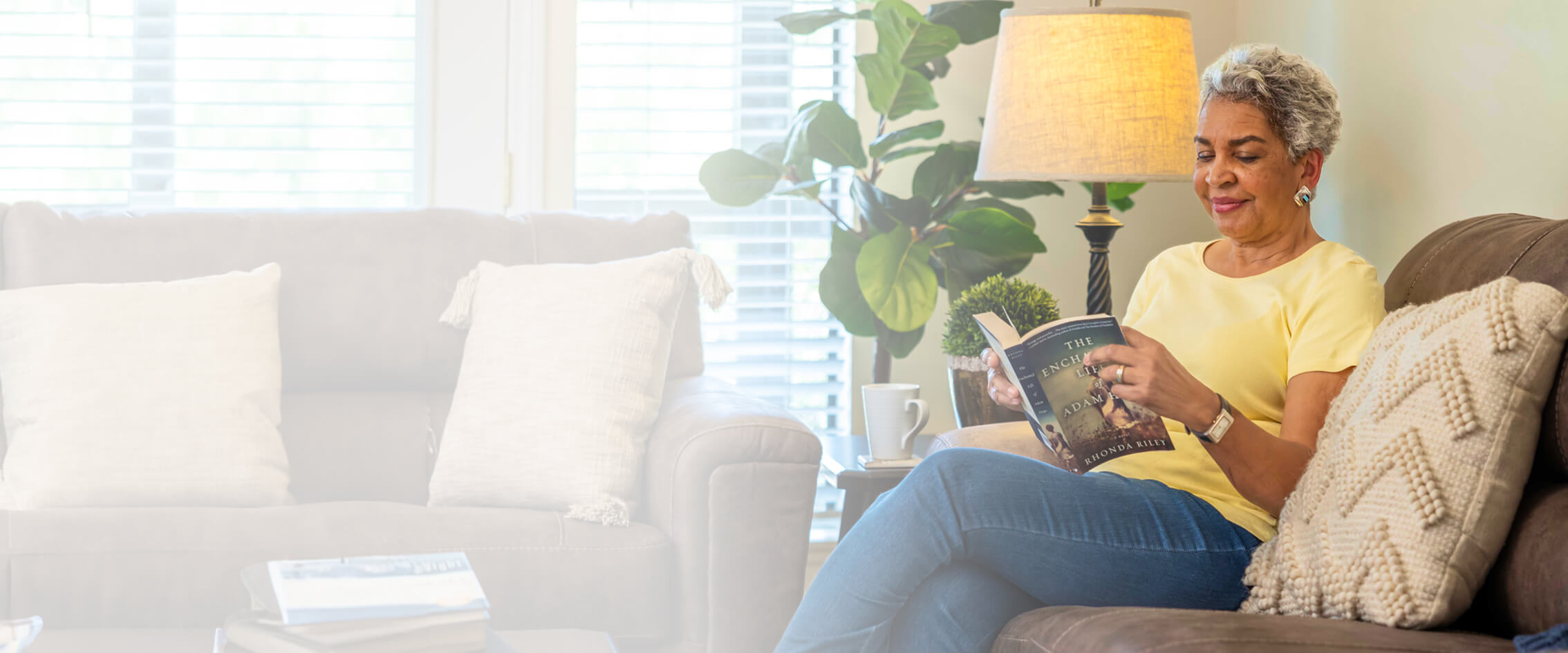 Senior woman sitting on a couch while reading a book