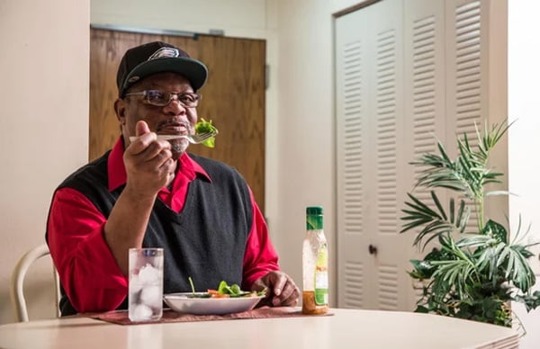 senior sitting at dining table while eating a healthy meal
