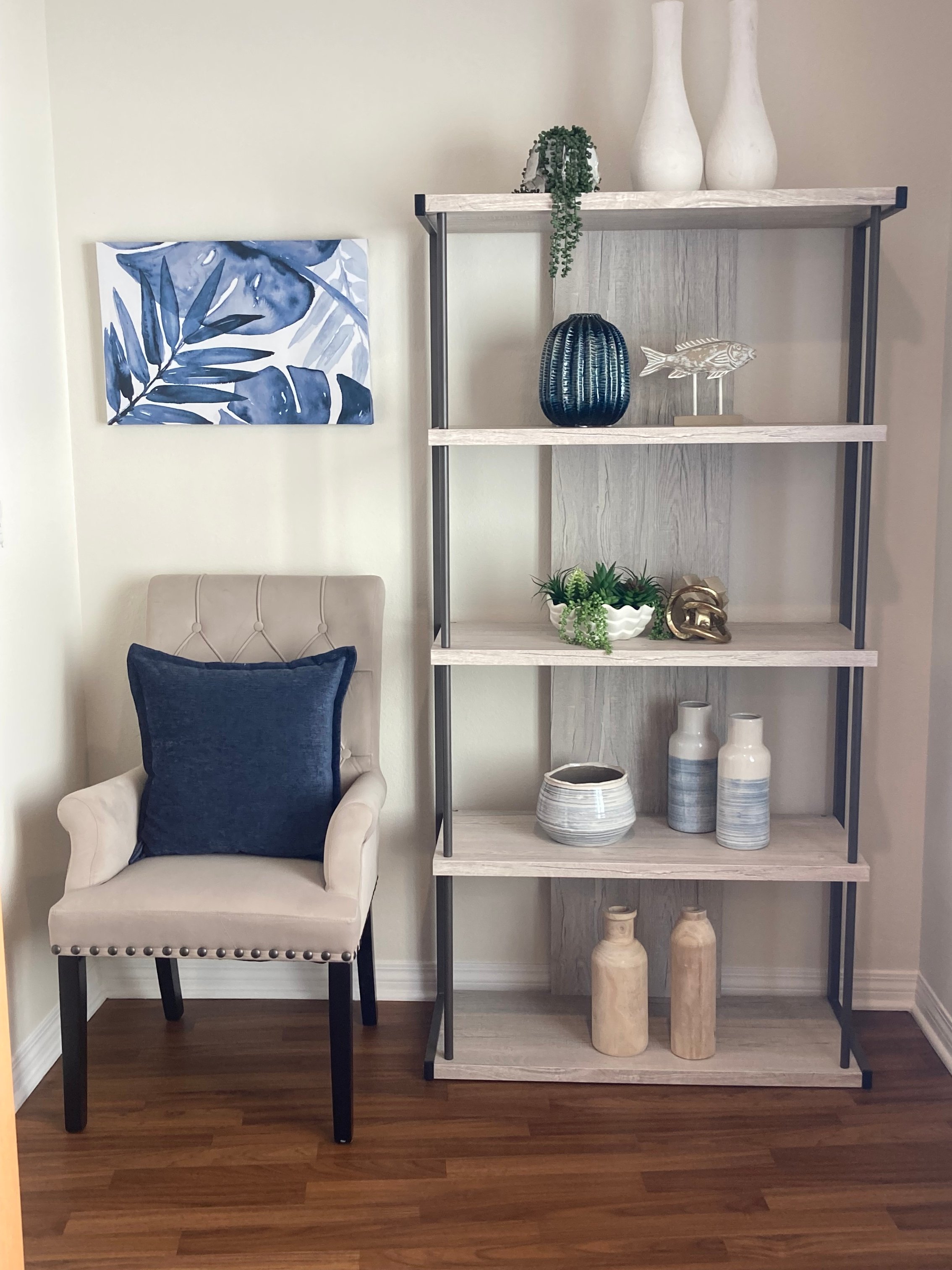 Cozy corner with a chair and decorative shelving in blue and neutral tones.