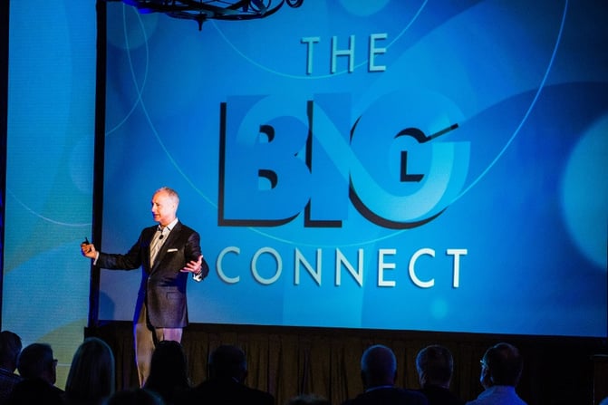Man speaking in front of a screen that reads "The Big Connect"