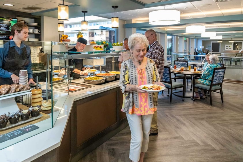 Residents sit together in a comfortable lounge at Judson Park, smiling and talking around a low table in a welcoming common area.