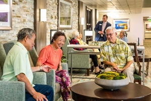 Residents relax and converse in a Judson Park community lounge while a staff member stands nearby, creating a friendly, social environment.