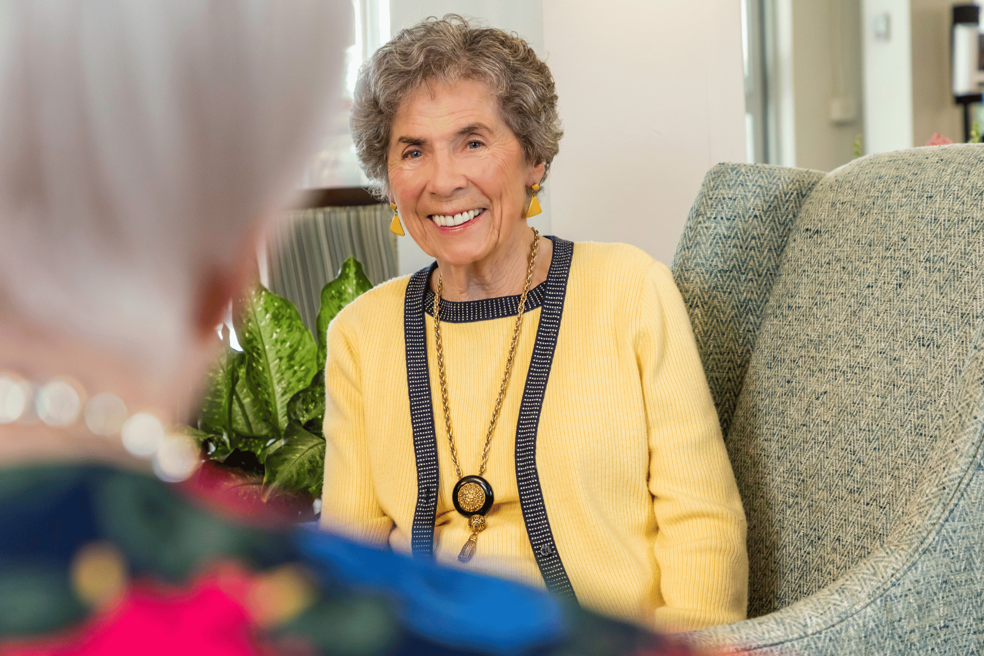 Image of a woman in a yellow sweater talking to a friend