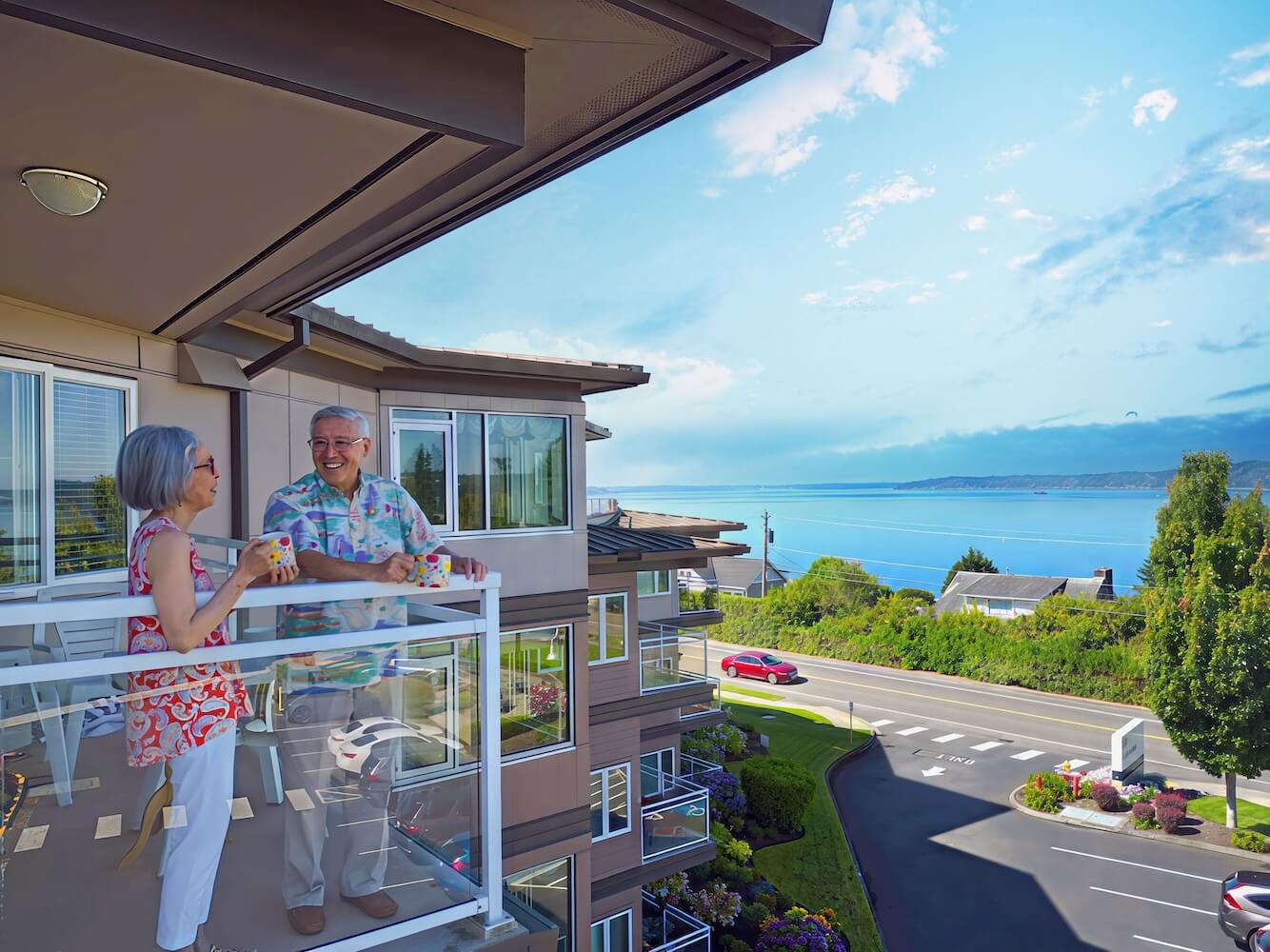 Senior couple standing on the balcony of an apartment at Judson Park overlooking the water