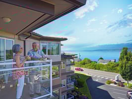 seniors standing on an apartment balcony overlooking the water