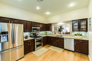 Kitchen with dark wood cabinets and stainless steel appliances of an apartment at Las Ventanas at Summerlin