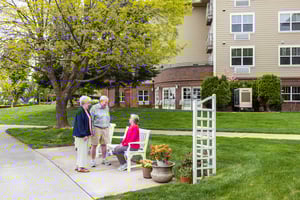 Senior woman on a park bench talking to a standing senior man and senior woman