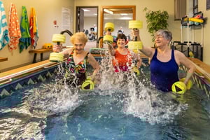 Three senior women using water weights in a water exercise class