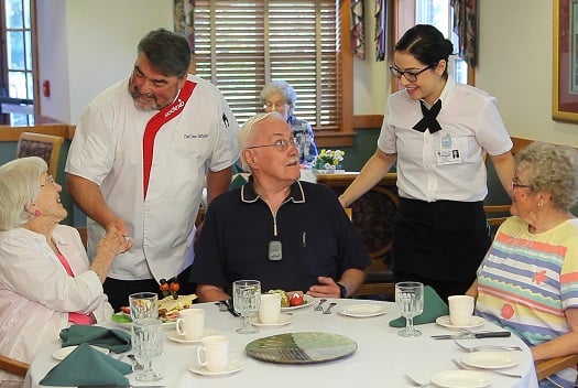 Chef and waitress talking to three people at a dinner table