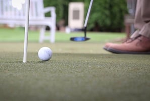 Close-up of a person putting a golf ball 