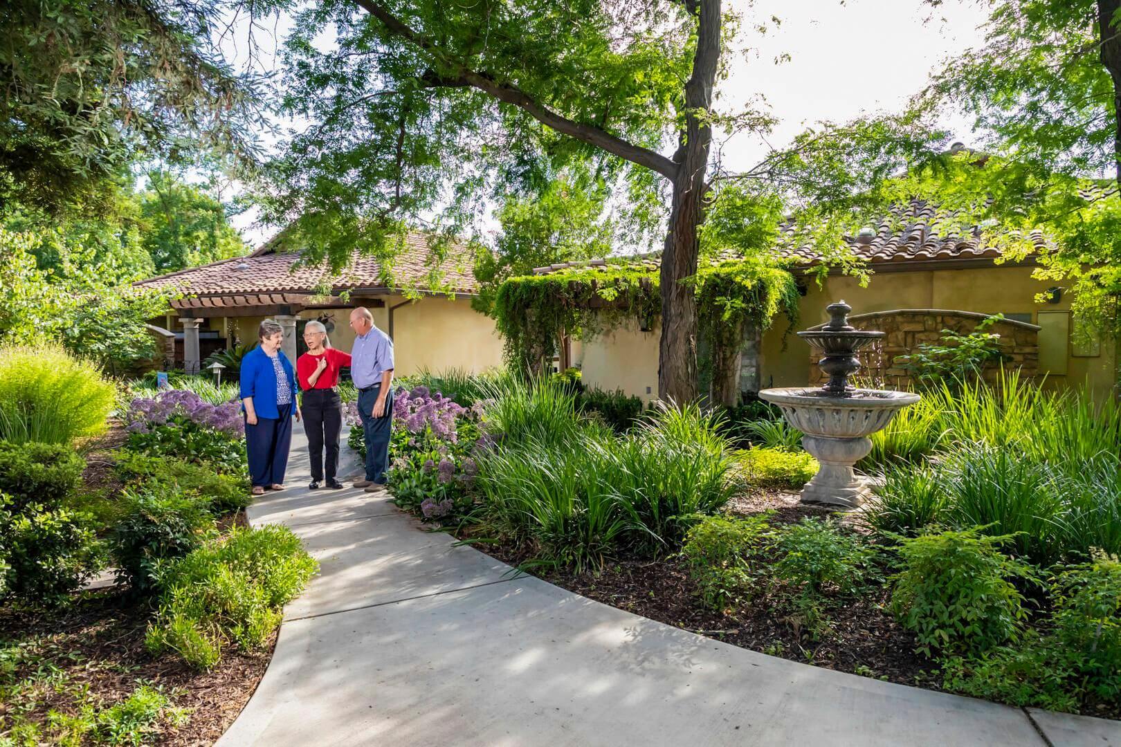 Three seniors standing on a path in the garden