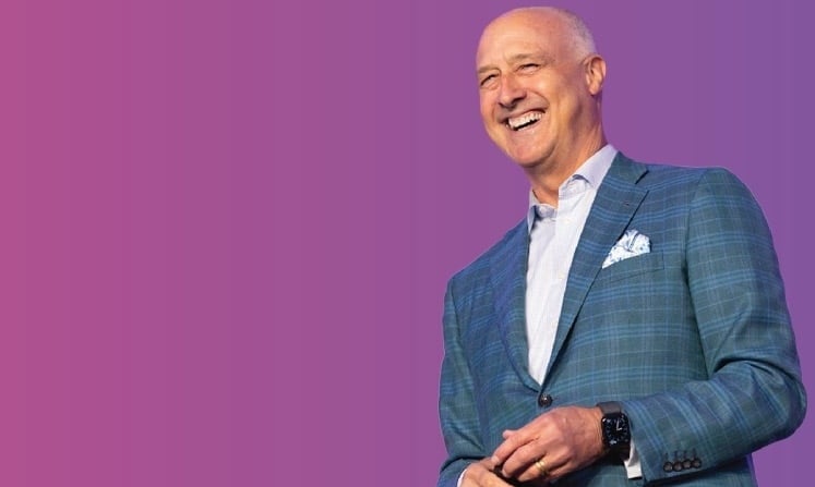 HumanGood CEO John Cochrane on a purple and pink gradient background.