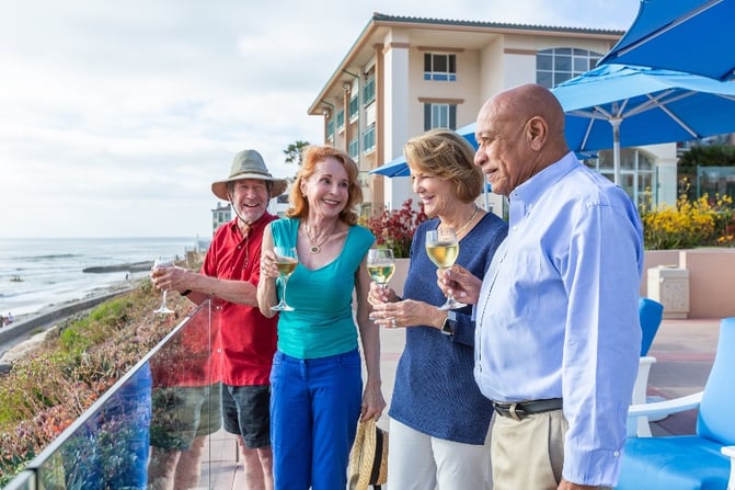 People standing on a patio at the beach with drinks in hand.