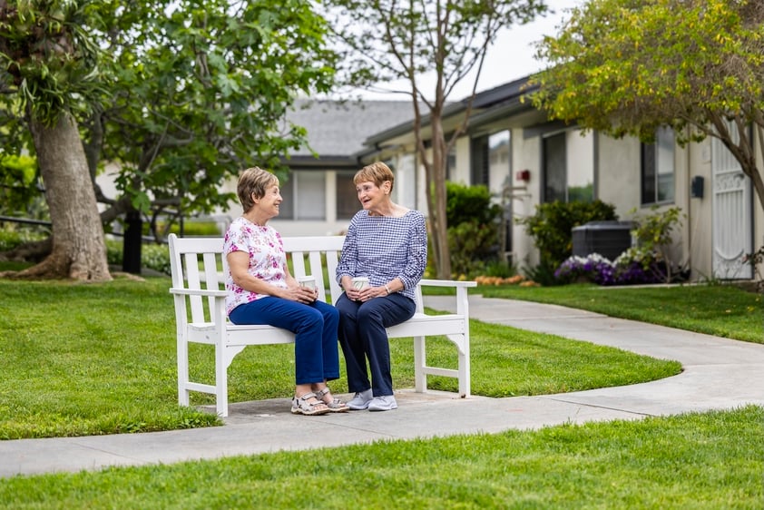 Two woman sitting and talking on a white bench