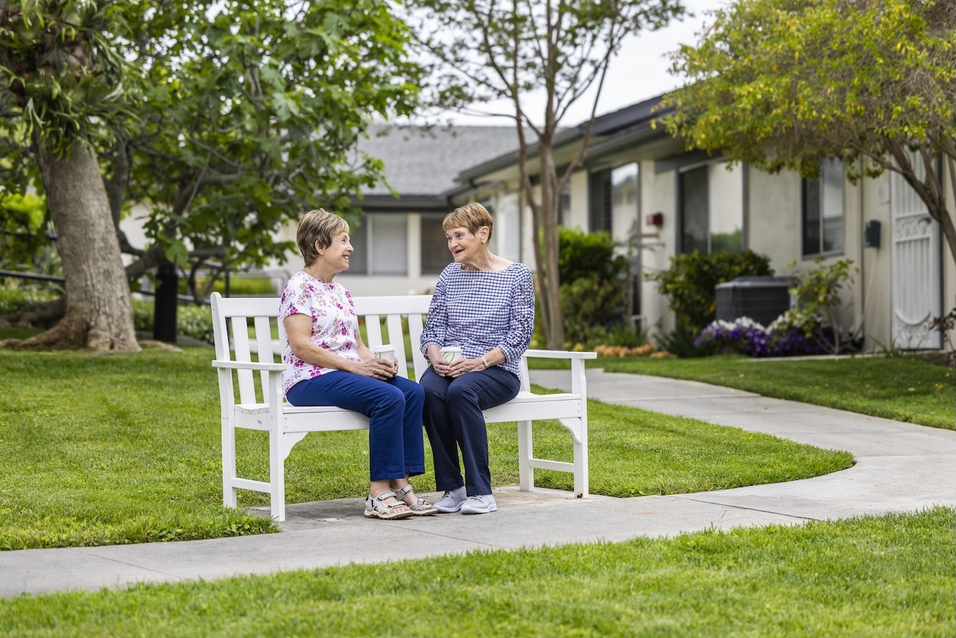 Two woman sitting and talking on a white bench