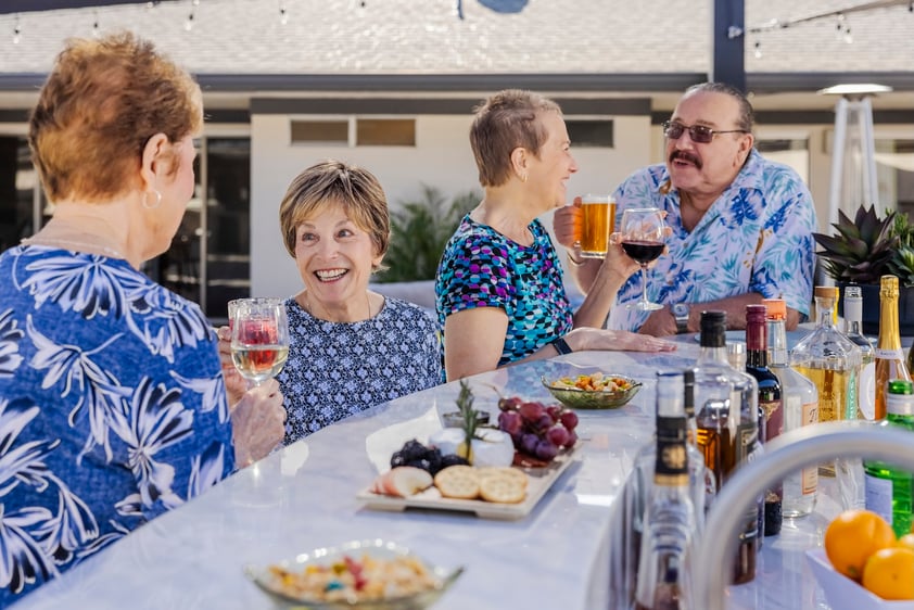 Four happy seniors enjoying drinks and snacks at an outdoor bar