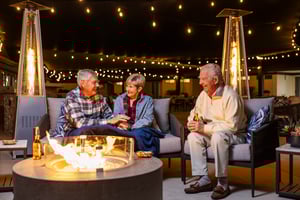 3 people sitting around a fire pit in the evening