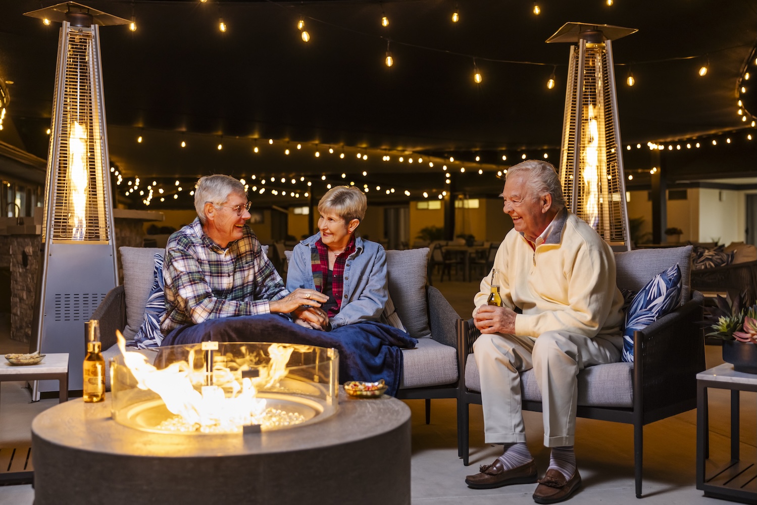 3 people sitting around a fire pit in the evening