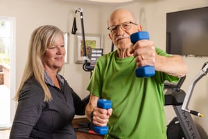 Trainer instructing senior man with weights