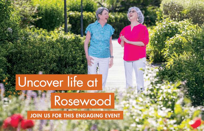 Two women walking and talking on a garden path surrounded by greenery