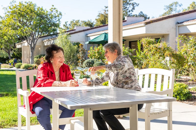 two seniors enjoying a bottle of white wine on an outdoor patio