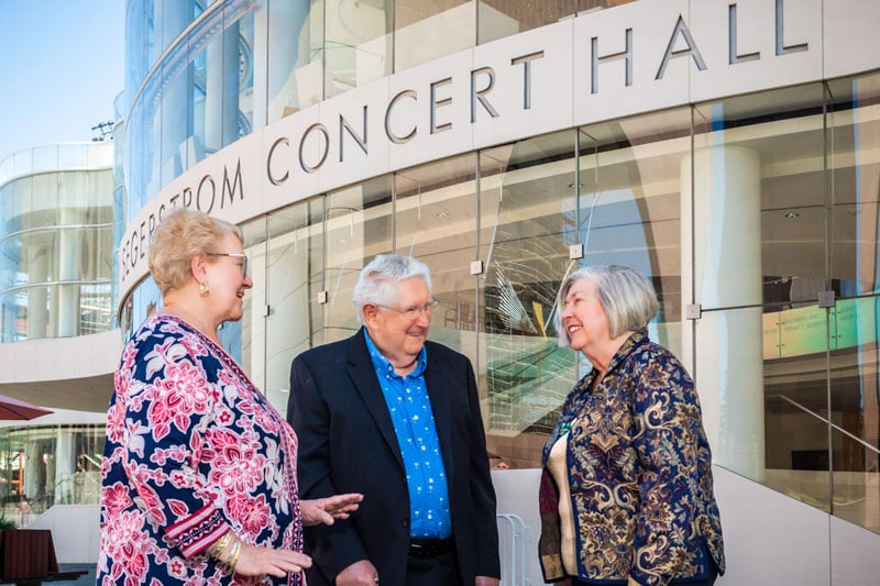 three seniors chatting in front of a concert hall