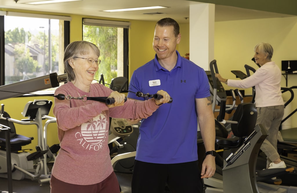 Senior woman working out in the gym with personal trainer