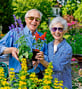 Mike and Linda holding up potted plants while gardening outside