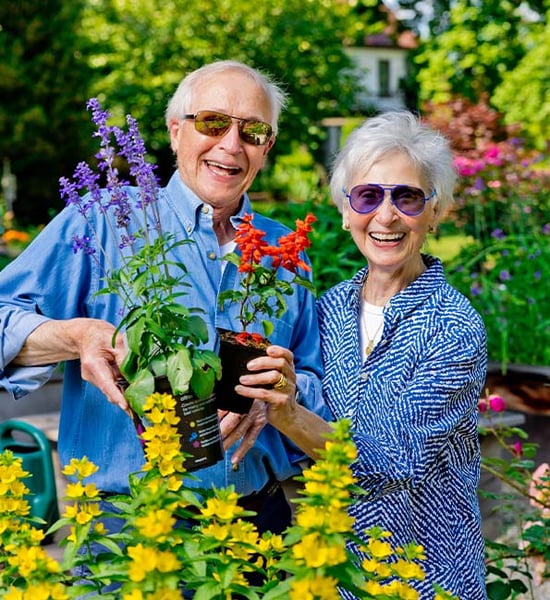 Mike and Linda holding up potted plants while gardening outside