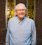 Paul smiling and standing near a lit window