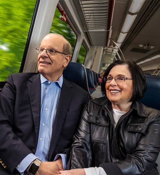 Stan and Jackie holding hands while riding a train